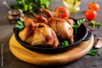 Baked quails in pan on a dark background