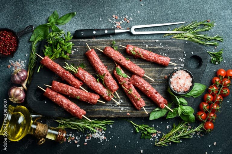 Raw Lyulya kebab with spices and herbs, ready for cooking. On a dark stone background. Top view....